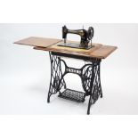A Singer treadle sewing machine in walnut case & on iron base, 36” wide.