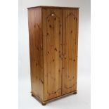 A pine wardrobe enclosed by pair of fielded panel doors, & on bun feet, 34” wide x 70” high.