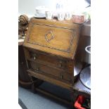 A 1930’s small oak bureau with fitted interior enclosed by fall-front above two long graduated