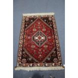 A Persian rug of crimson ground, with central lozenge, deep blue spandrels, & cream ground narrow