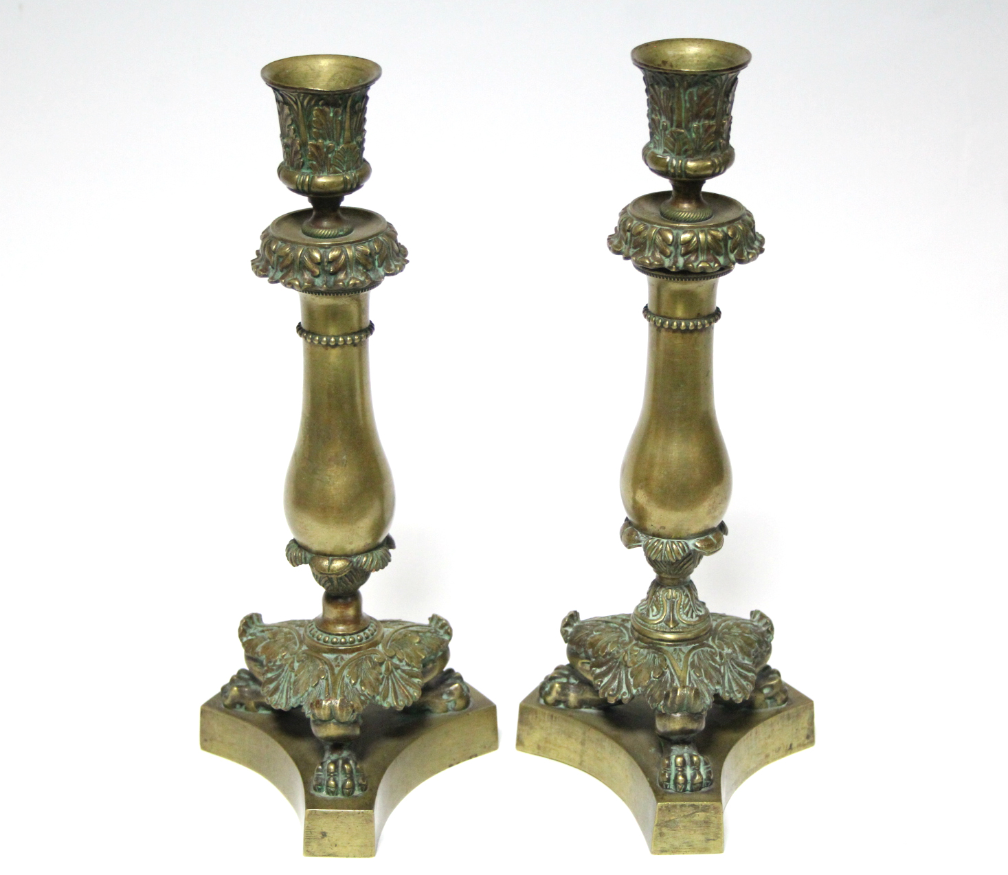 A pair of early 19th century bronze candlesticks with cast foliate nozzles, plain baluster stems,