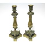 A pair of early 19th century bronze candlesticks with cast foliate nozzles, plain baluster stems,