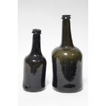 A late 18th/ early 19th century dark green glass wine bottle, 9¾” high; & a similar bottle, 8”.