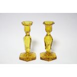 A pair of mid-19th century amber glass candlesticks, each with seven-sided baluster column on