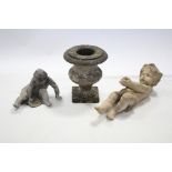 A lead figure of a seated putto, 8” high; a composition putto figure, 23” high; & a carved stone