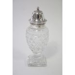 A cut glass vase-shaped sugar sifter with pierced silver cover, on square pedestal foot, 6½” high;