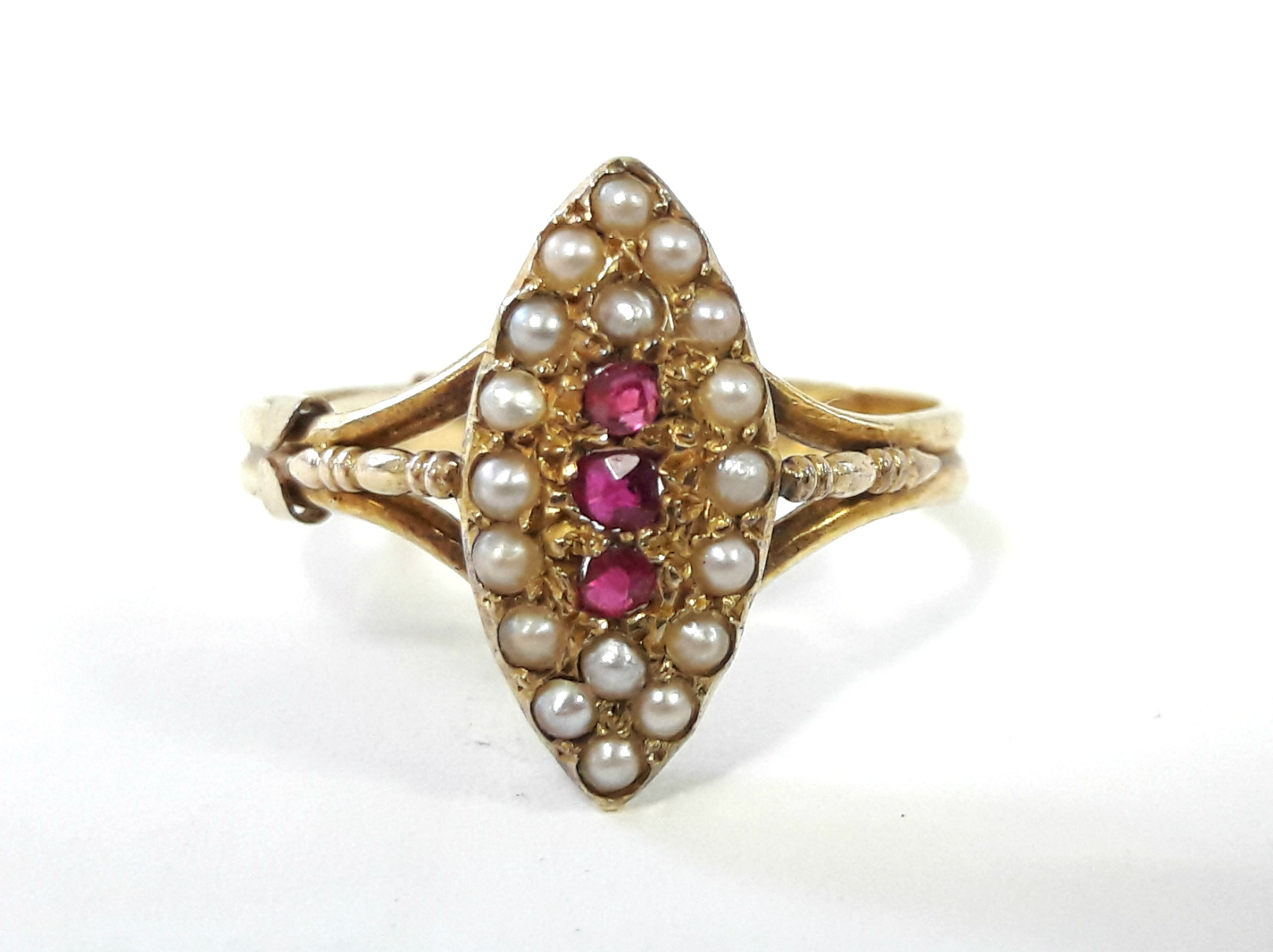 A 15ct. gold ring with navette shaped panel set three small rubies surrounded by seed pearls.
