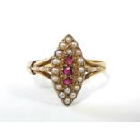 A 15ct. gold ring with navette shaped panel set three small rubies surrounded by seed pearls.