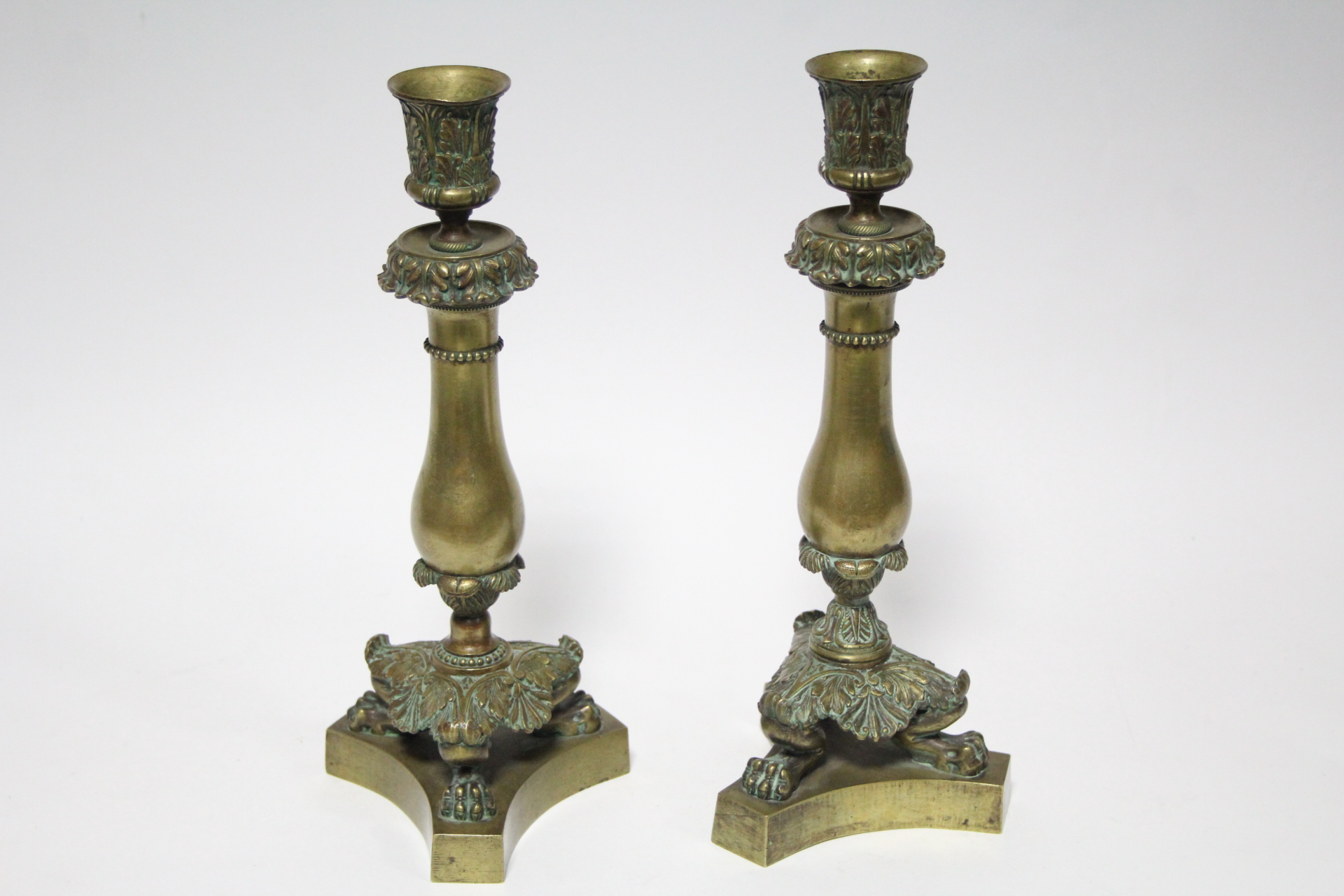 A pair of early 19th century bronze candlesticks with cast foliate nozzles, plain baluster stems, - Image 2 of 2