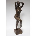 A bronzed composition sculpture of a nude female dancer, 24” high, on wood block base. (w.a.f.).