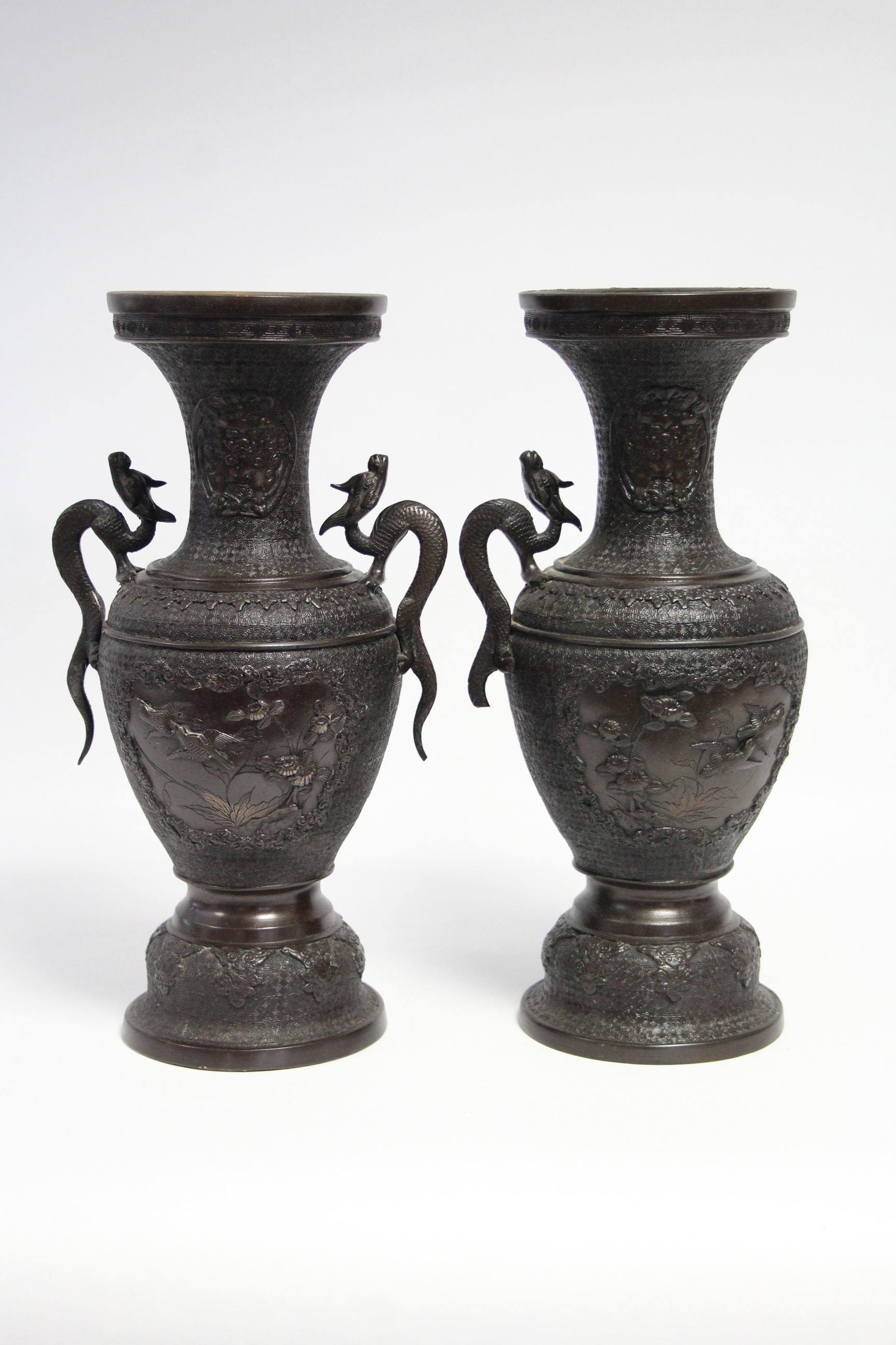287. A pair of Chinese bronze ovoid vases with dragon side handles decorated with birds & shrubs