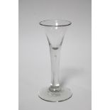 An 18th century drinking glass with trumpet-shaped bowl, tear-drop to the plain stem, & on plain