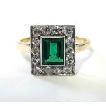 AN EMERALD & DIAMOND RING, the centre rectangular emerald set within a border of fourteen small