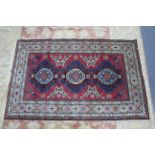 A Nessims Persian pattern rug of crimson & blue ground with three medallions to centre, & with