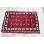 A Persian patter rug of crimson & ivory ground with three rows of six guhls to centre within a