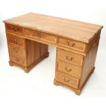 A pitch pine pedestal desk fitted with an arrangement of eight drawers with brass swan-neck handles,