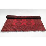 An Afghan small carpet of crimson & black ground with two rows of five guhls to centre within a wide