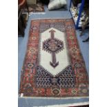 A Persian rug with cream ground centre with arrow-head medallion, within wide crimson floral border;