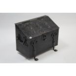A black-finish metal sloping-front log box with hinged lift-lid, wrought-iron side handles & on