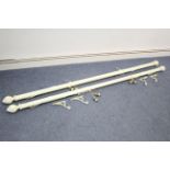 A pair of white painted & carved wooden curtain poles, 84” long with fittings.