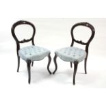 A pair of Victorian carved beech balloon-back occasional chairs with buttoned padded seats on