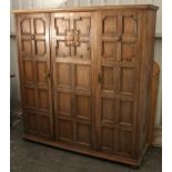 An 18th century-style oak wardrobe with fitted interior enclosed by three fielded panel doors & on