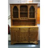 A Ducal pine dresser, the upper part fitted three shelves & enclosed by pair of glazed end doors