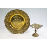 A brass circular wall plaque with embossed foliate design to border & with embossed female