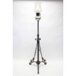 A wrought-iron telescopic standard lamp on triform base, & with glass reservoir & shade.