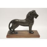 A bronzed composition model of a standing lion, 10" high x 13" wide, on oak base.