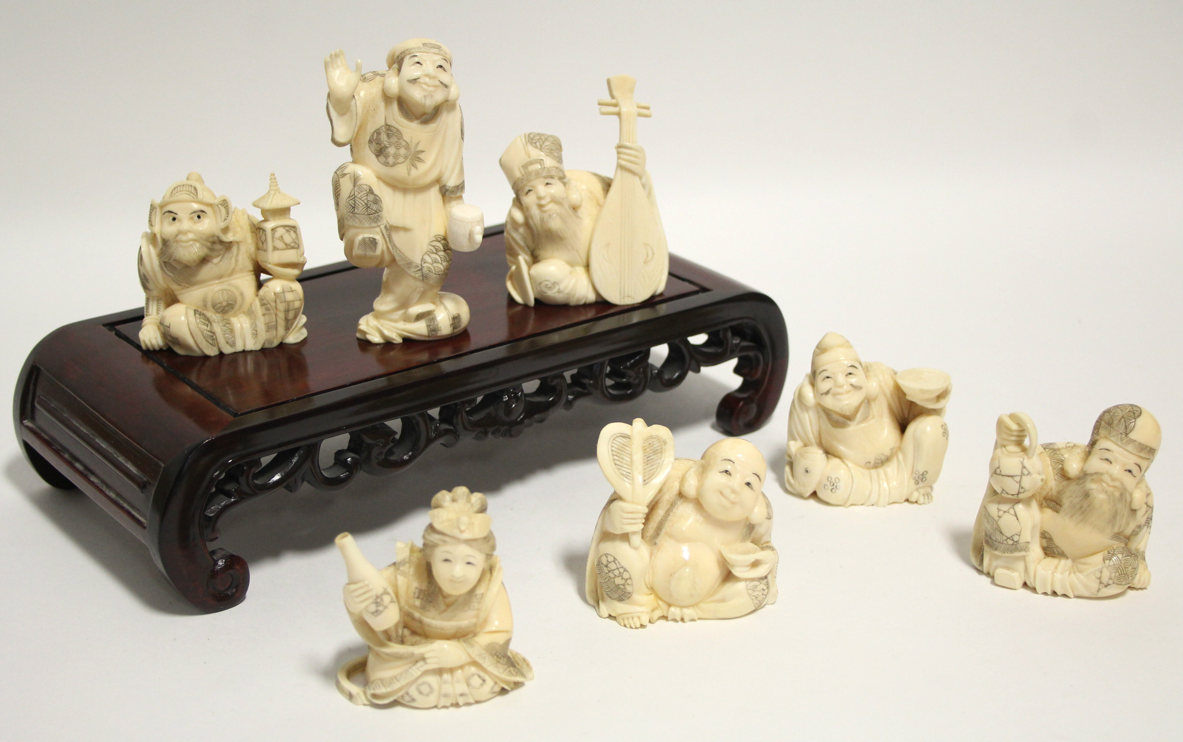 A GROUP OF SEVEN JAPANESE CARVED MARINE IVORY OKIMONO, comprising a standing male figure holding a