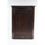 A late 18th century mahogany hanging corner cupboard with inlaid decoration to the panel door,