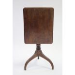 An early 19th century mahogany tripod table with rectangular tilt-top on turned centre column &