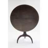 An early 19th century oak tripod table with circular tilt top on ring-turned centre column & three