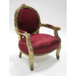 A Louis XVI style carved giltwood frame child’s elbow chair with rounded padded back, arms, &