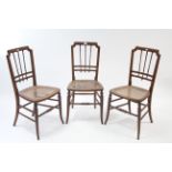 A set of three late 19th century ash spindle-back occasional chairs with woven cane seats, & on