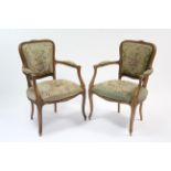 A pair of continental-style carved beech frame elbow chairs with padded backs & sprung seats