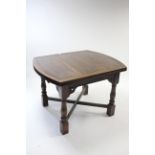 A mid-20th century oak draw-leaf dining table with rounded ends to the rectangular top, & on