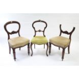 A pair of Victorian walnut balloon-back dining chairs, each with carved centre rail, padded seat &