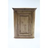 A pine hanging corner cupboard fitted two shaped shelves enclosed by fielded panel door, 29½” wide x