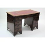 A reproduction mahogany pedestal desk inset gilt-tooled crimson leather to top, fitted nine