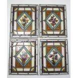 A set of four leaded & stained-glass window panels with floral design to centre, 15¼” x 12¼”; & a
