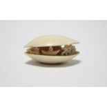 A Chinese ivory clam shell netsuke with carved & pierced figure & tree design to centre, 1¾” wide.