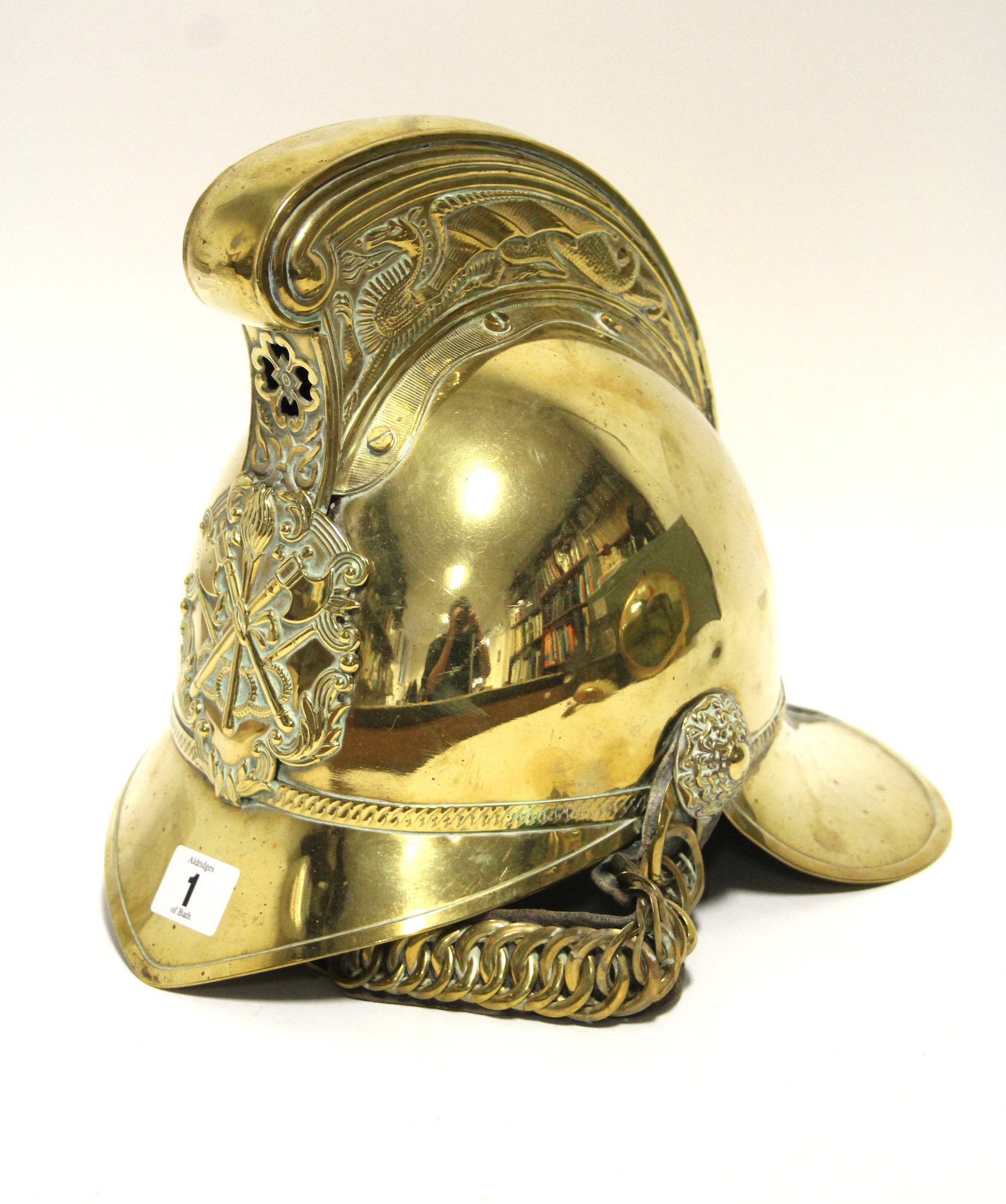 AN ANTIQUE BRASS FIREMAN’S HELMET BY RIDER & BELL, WITH LEATHER CHIN-STRAP.