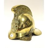 AN ANTIQUE BRASS FIREMAN’S HELMET BY RIDER & BELL, WITH LEATHER CHIN-STRAP.