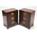 A pair of campaign-style mahogany three-drawer bedside chests with brass handles & mounts, & on