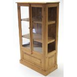 A pine display cabinet fitted two shelves enclosed by pair of glazed doors above a fall-front & on