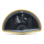 A display of a black fabric fan with painted classical figure scene decoration; and in glazed gilt