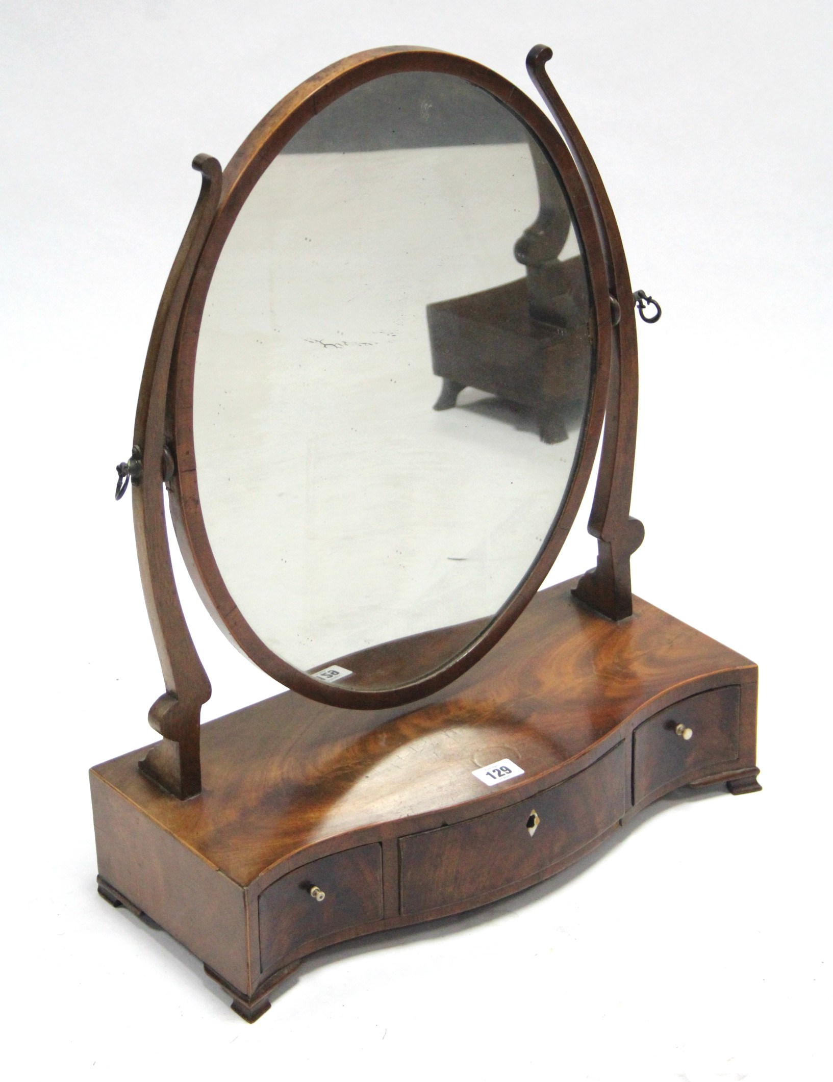 A 19th century inlaid-mahogany oval swing toilet mirror fitted three drawers to the serpentine-front