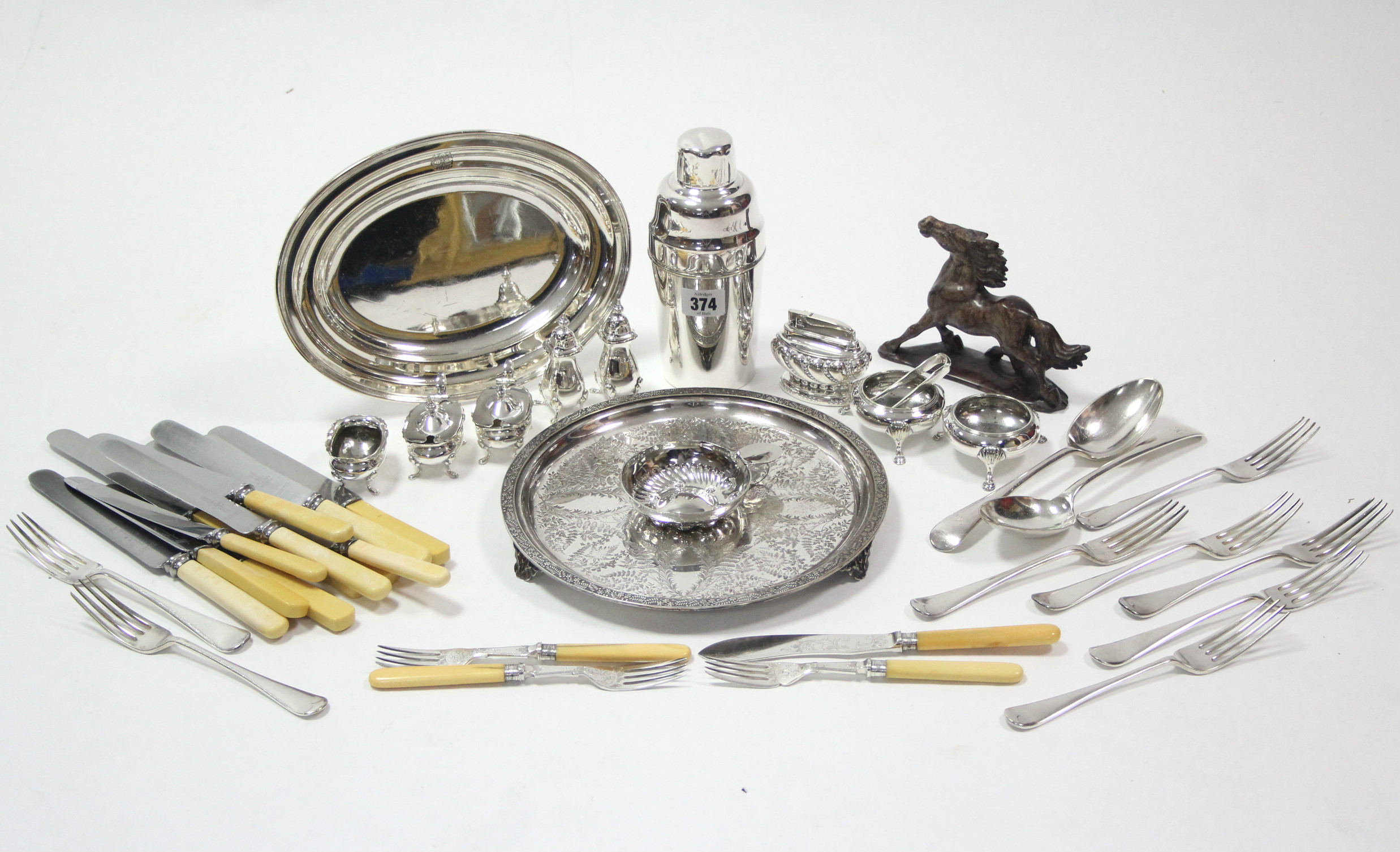 A silver plated cocktail shaker; an engraved silver-plated circular tray; an oval dish; seven plated